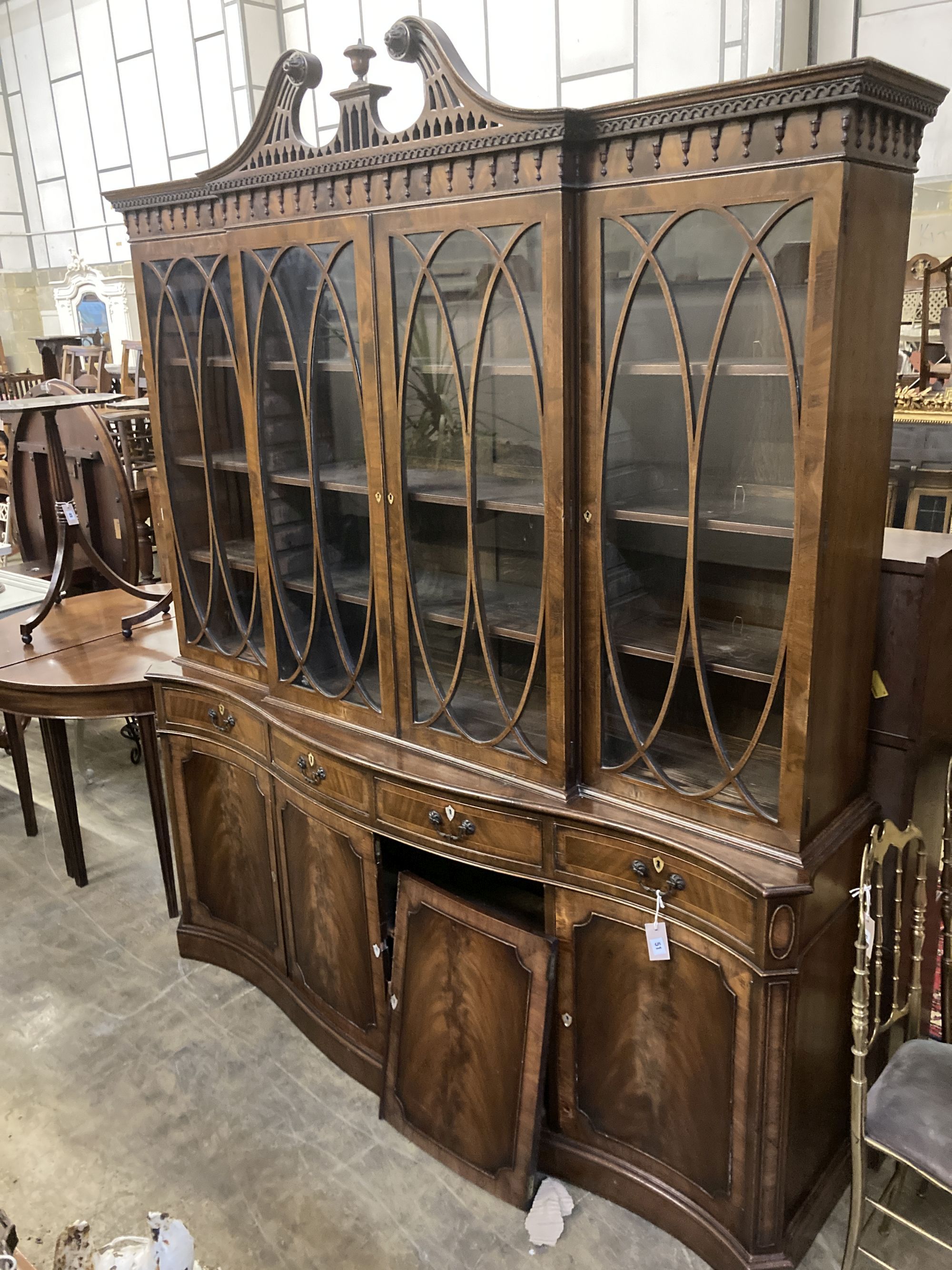 A George III style mahogany and walnut banded breakfront bookcase, with pierced broken swan neck pediment over oval glazing bars,